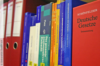 Mehre juristische Bücher stehen nebeneinander auf einem Regal.